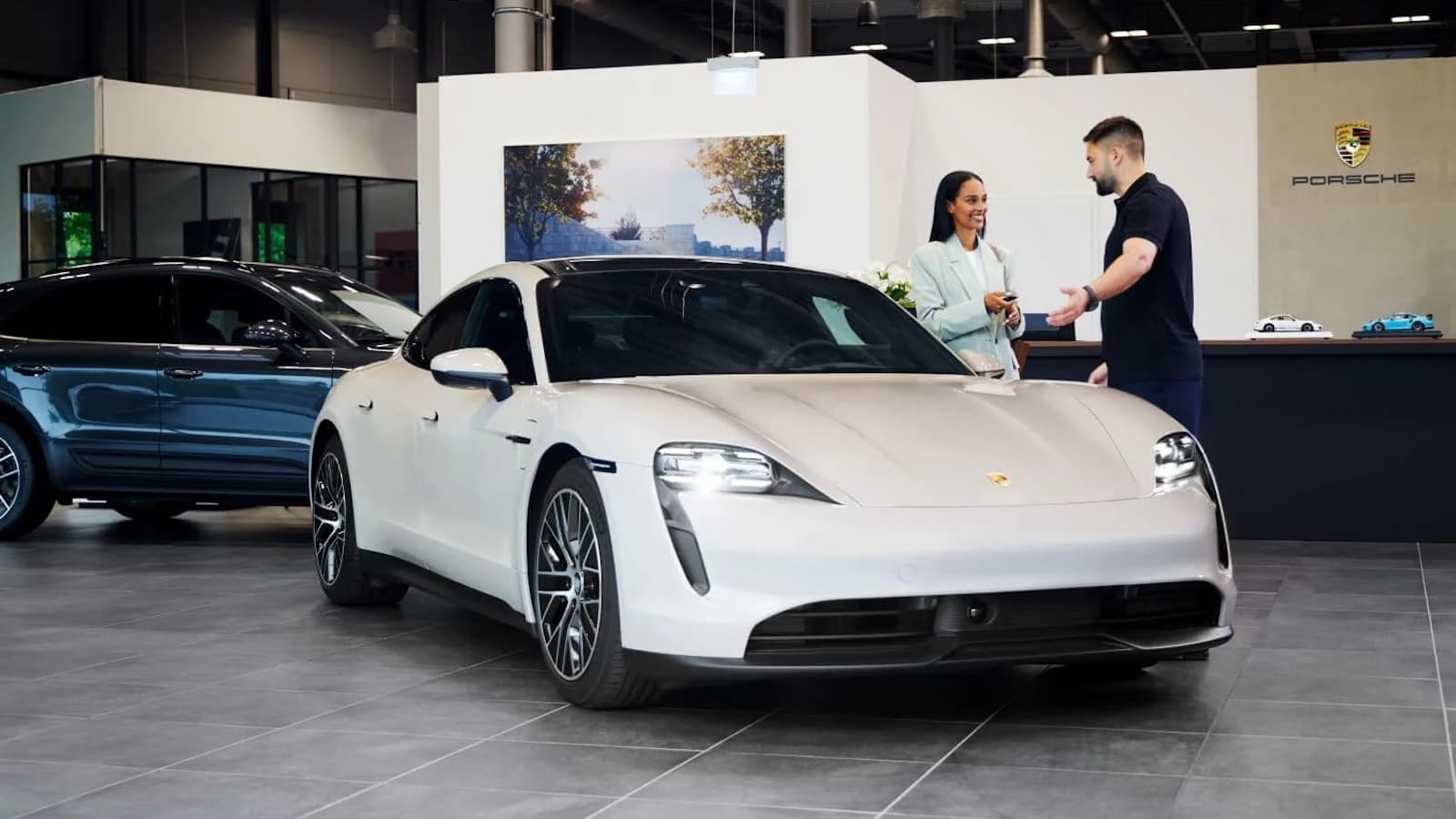A happy Porsche Drive Rental customer getting the keys to a Porsche Taycan
