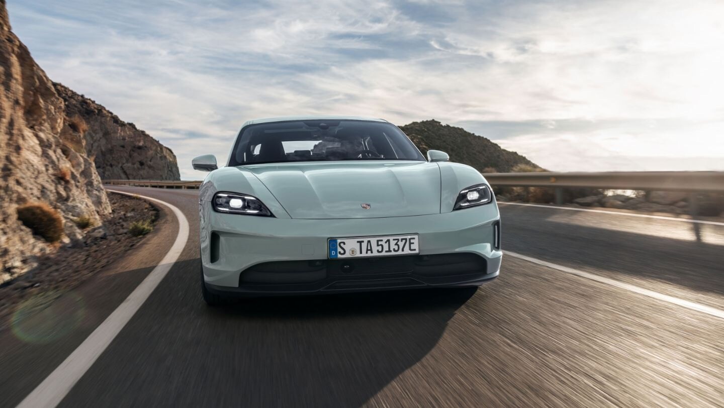 Blue Porsche Taycan driving down a windy road