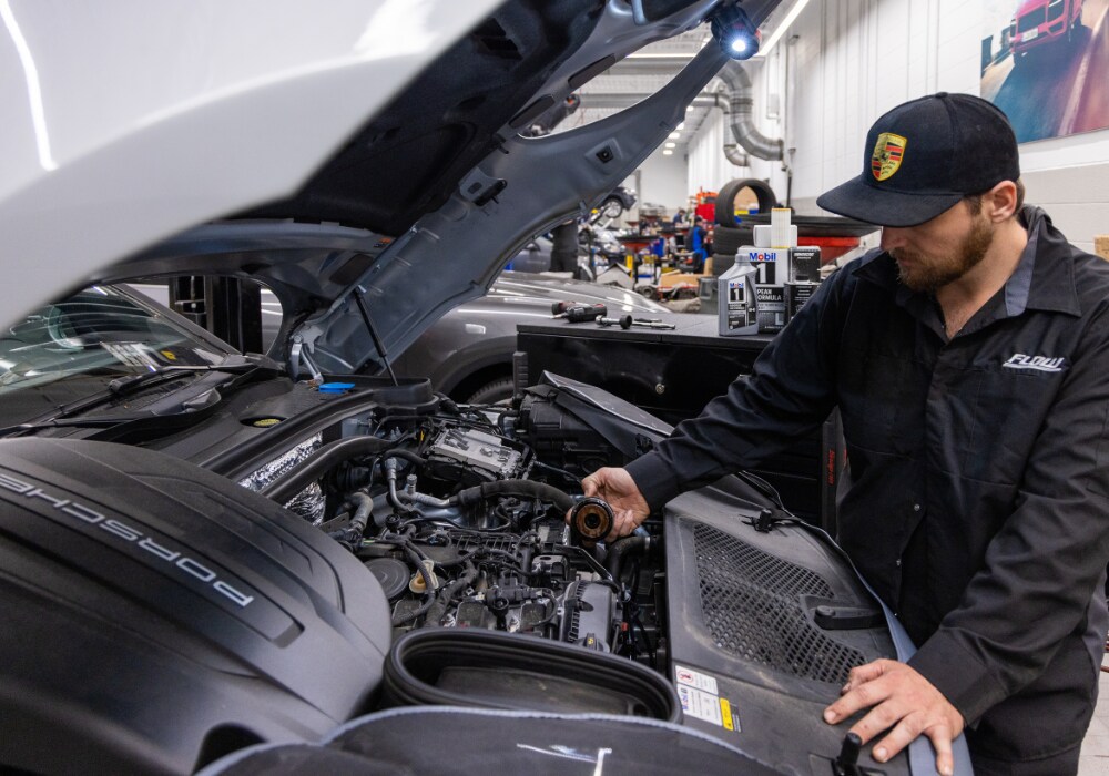 porsche-service-coupons.png Porsche service technician looking under the hood of a car