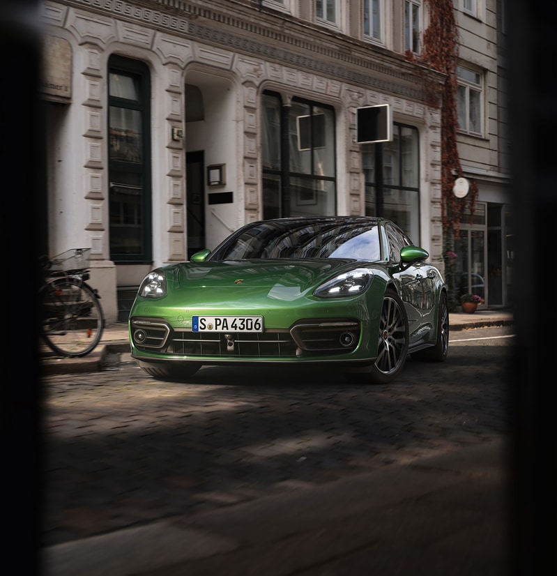 2024-Porsche-Panamera-TurboSSportTurismo-Hatchback.png green Porsche Panamera Turbo S Sport Turismo driving on a cobblestone street