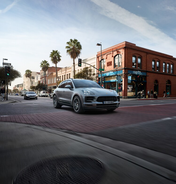 2024-Porsche-Macan-Base-SUV.png silver Porsche Macan driving through the Downtown L.A. area