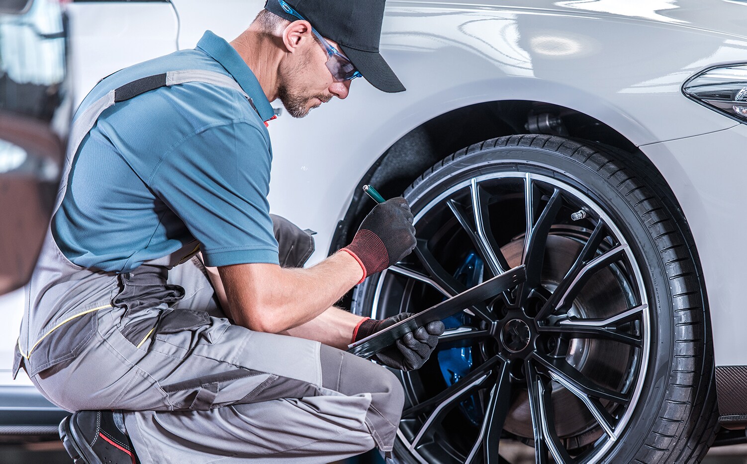 Porsche Towson is a Porsche Dealership near Baltimore MD | Man servicing car and fixing wheel alignment