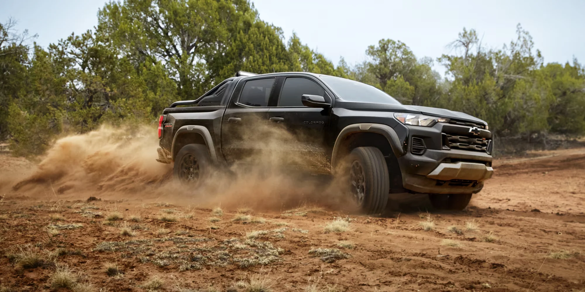Chevy Colorado on a dirt road throwing dust, showing four-wheel drive traction on loose surfaces