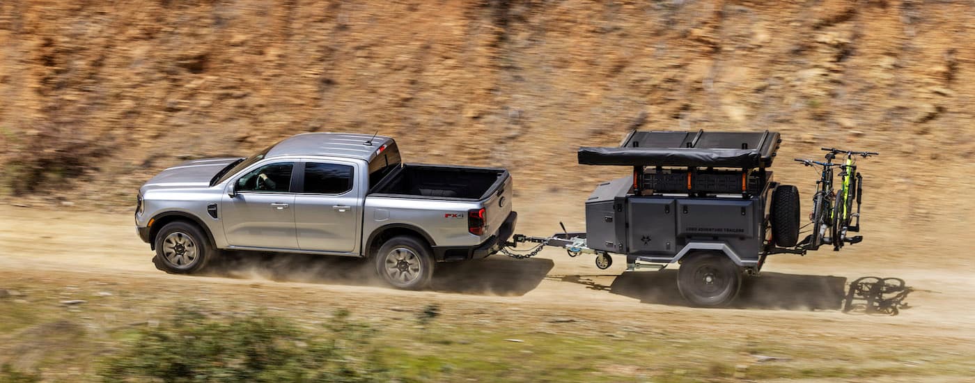 Ford Dealer wlp - All-New Ford Ranger Lariat_11.jpg A silver 2024 Ford Ranger Lariat towing a trailer after leaving a Ford dealer.