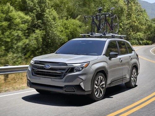 2026 Subaru Forester driving with a bike on roof rails