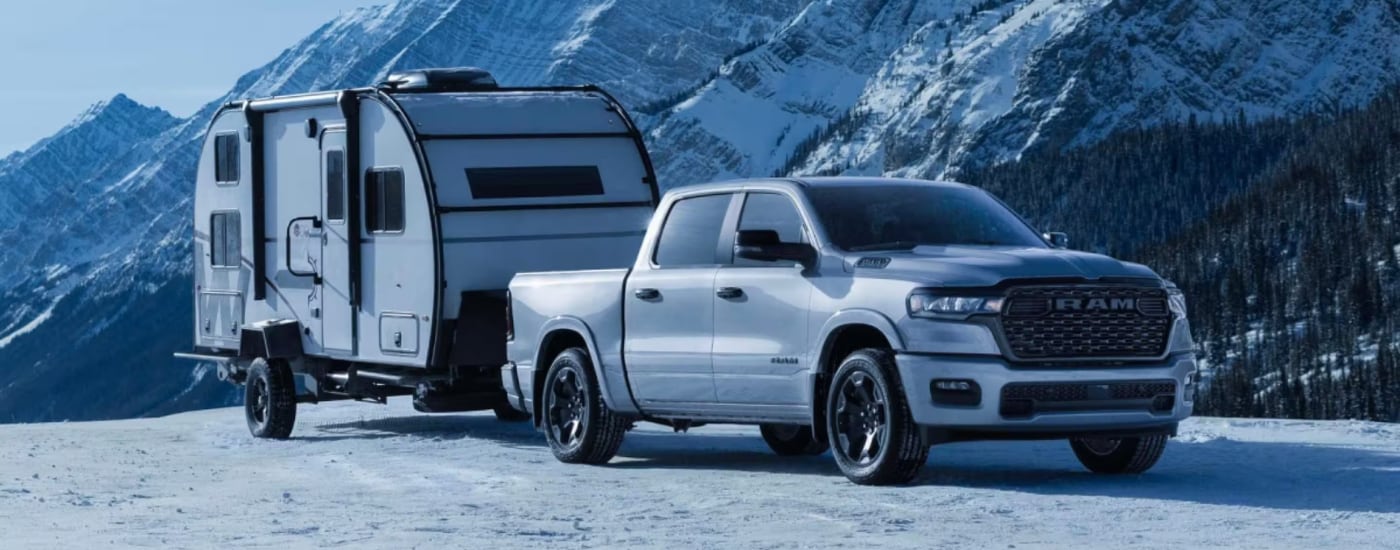 2026%20Ram%201500%20-%20capability.png White 2026 Ram 1500 towing a camper on a snowy mountain