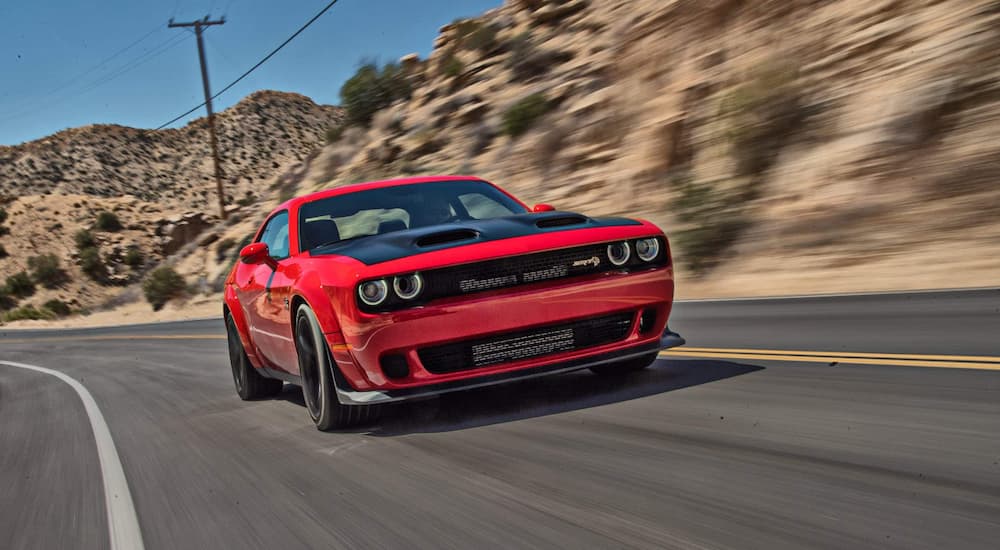 A red 2022 Dodge Challenger SRT Hellcat Redeye Widebody is driving on an open road.