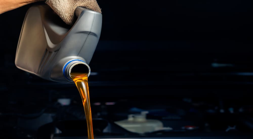 A large bottle of engine oil is being poured into an engine.