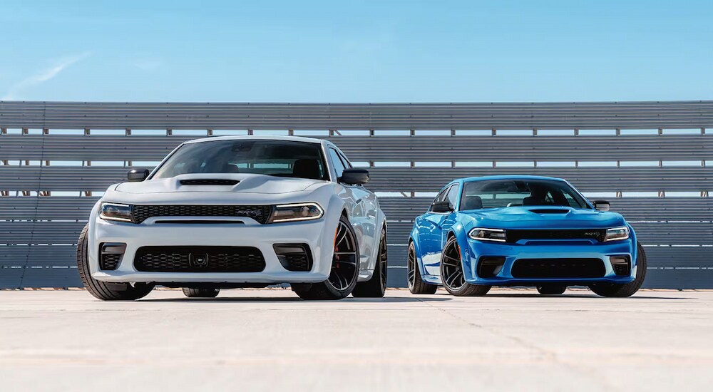 A white and a blue 2023 Dodge Charger SRT Hellcat Redeye Jailbreak are parked.
