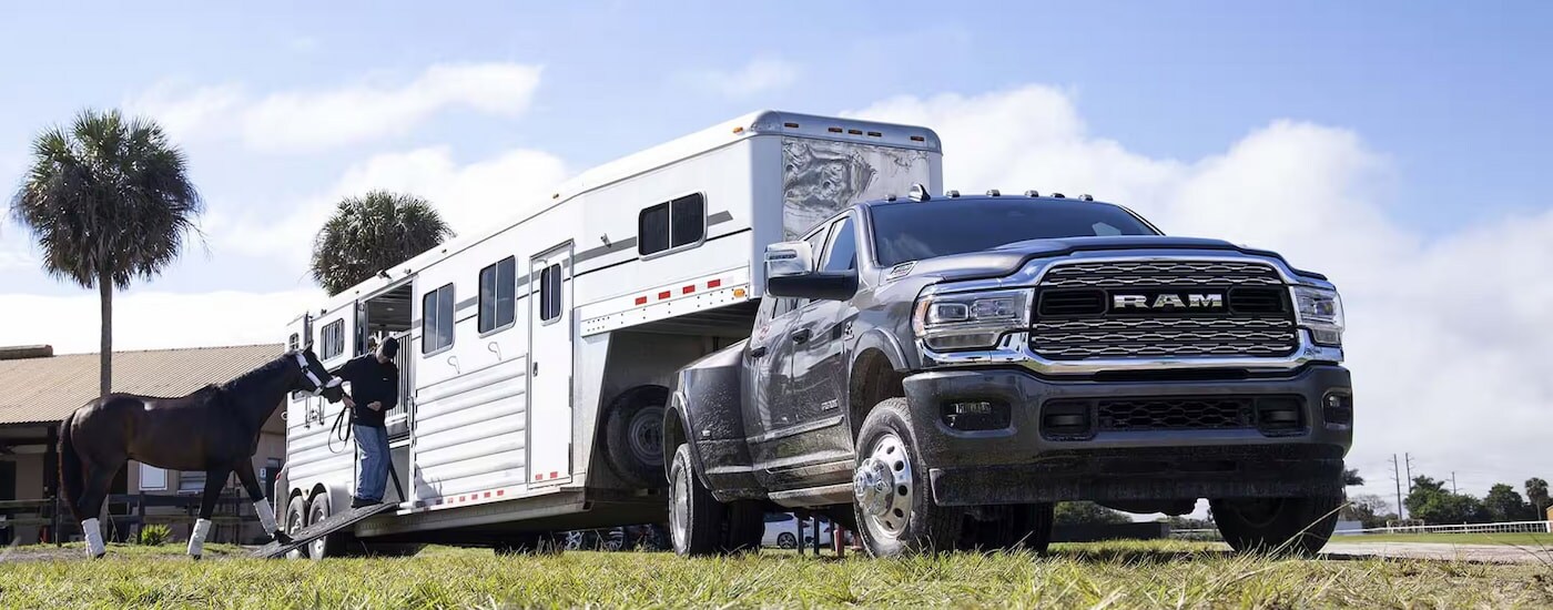 A large horse trailer connected to a black 2024 Ram 3500 for sale.