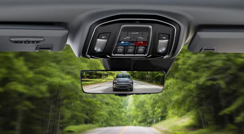 A close up of a used 2023 Jeep Grand Cherokee for sale in a rear view mirror.