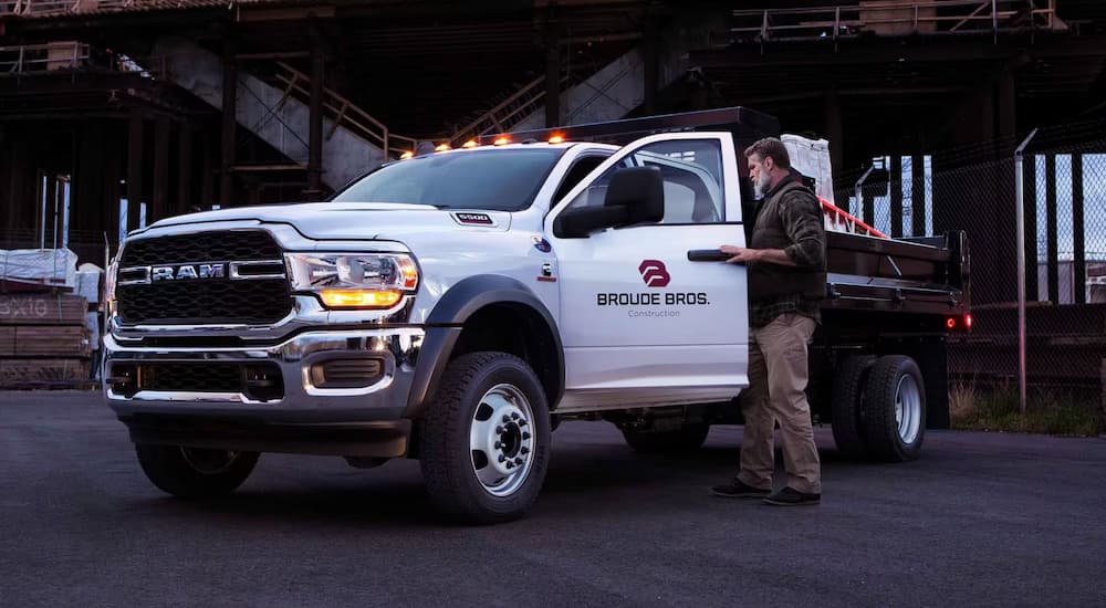 A man is opening the door of a white 2024 Ram 5500 at a construction site.