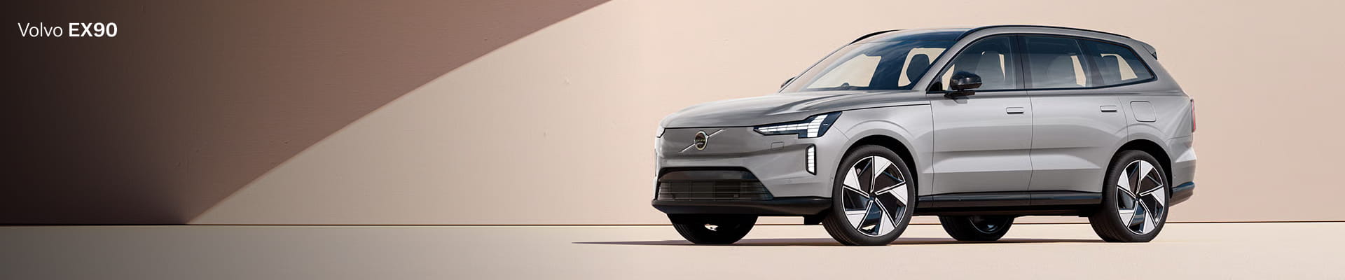 Sleek silver Volvo EX90 SUV set against a minimalist beige backdrop.