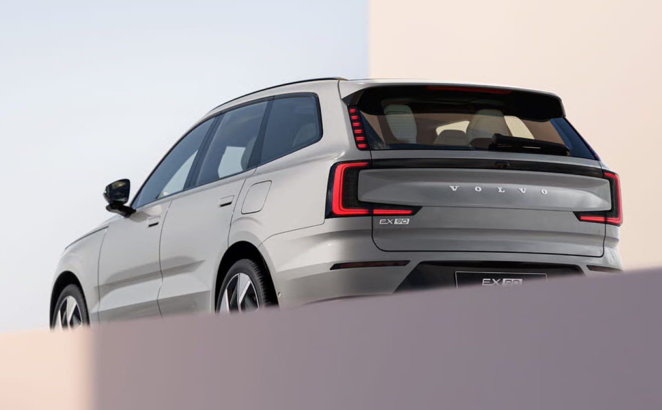 A sleek Volvo EX90 SUV is shown from behind, highlighting its modern design and distinctive taillights.