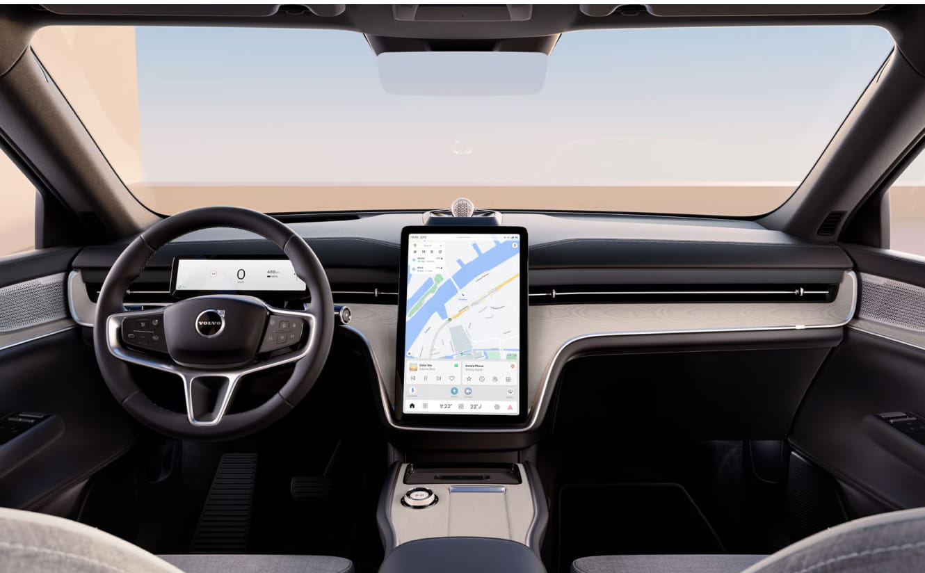 Volvo EX90 interior with a sleek, minimalist dashboard, a large central tablet screen displaying a map, and a modern steering wheel.