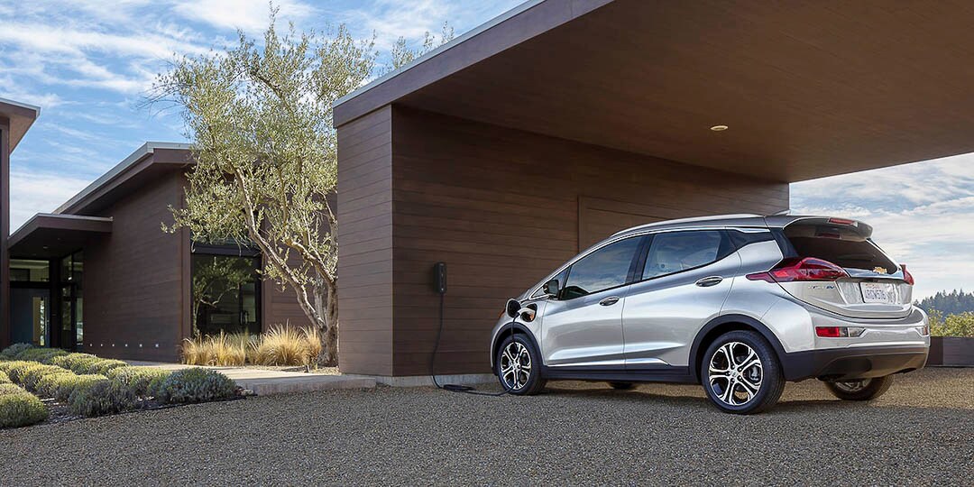 vue trois quart arrière du Chevrolet Bolt EV 2021 stationné et branché sur une borne de recharge