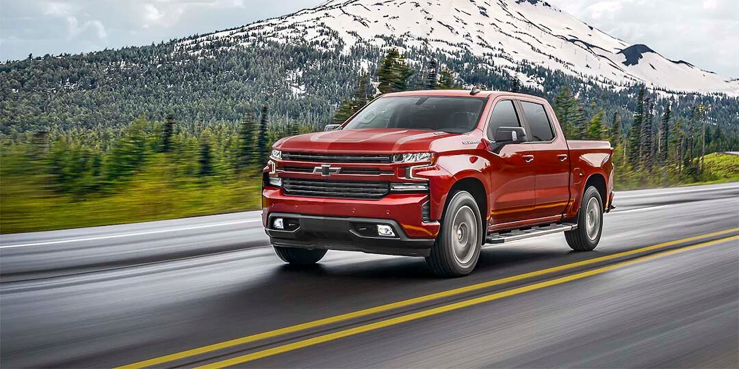 vue latérale du Chevrolet Silverado 1500 2021 roulant sur une route avec une montagne en arrière plan