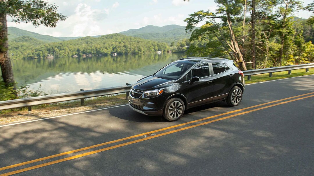 vue latérale du Buick Encore 2021 roulant sur une route proche d'une étendue d'eau