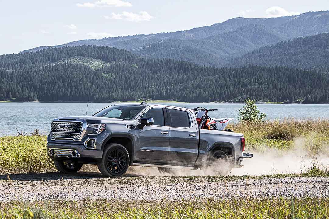 vue latérale du GMC Sierra 1500 2021 sur un sentier proche d'une étendue d'eau