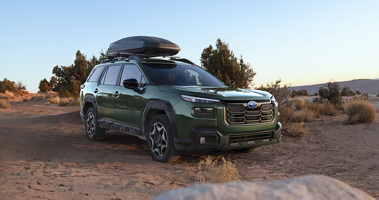 Side profile of a 2026 Subaru Outback in Mahwah driving on a wet road with Symmetrical All-Wheel Drive.