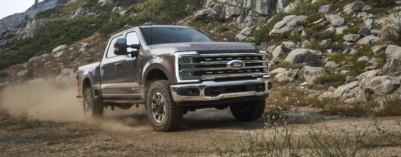 Trucks for Sale Near Toledo 2023 Ford F-250 Tremor - Dust.jpg Grey 2025 Ford F-250 Tremor truck for sale near Toledo driving on a dusty dirt road