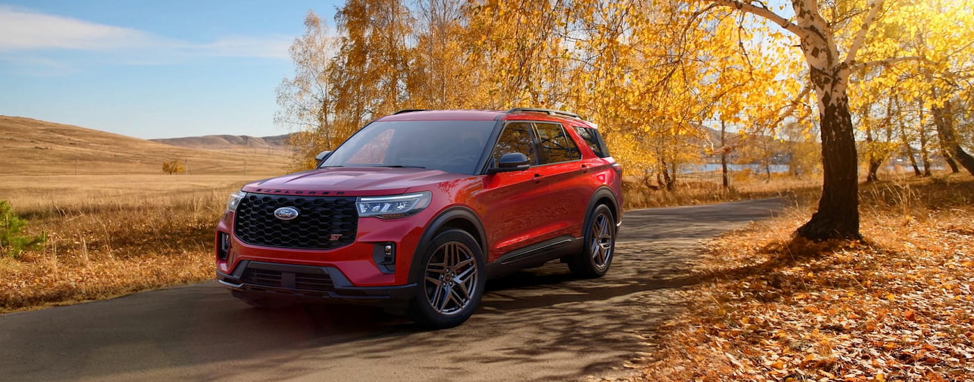 Red 2025 Ford Explorer ST driving down a road.