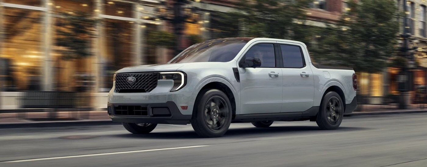 White 2026 Ford Maverick driving down a city street.