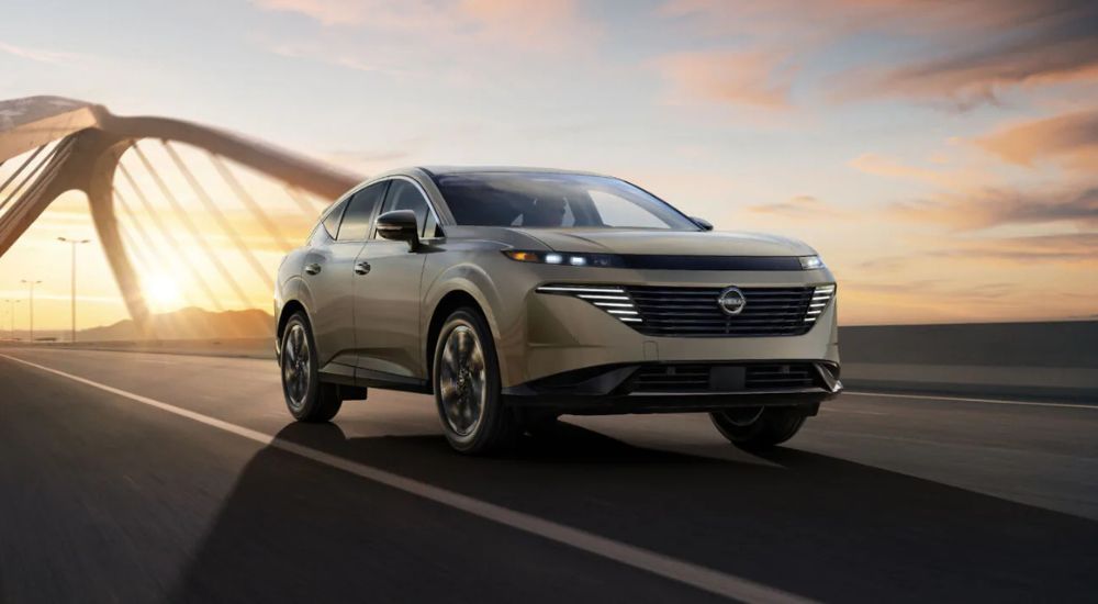A tan 2025 Nissan Murano Platinum driving across a bridge at sunset.