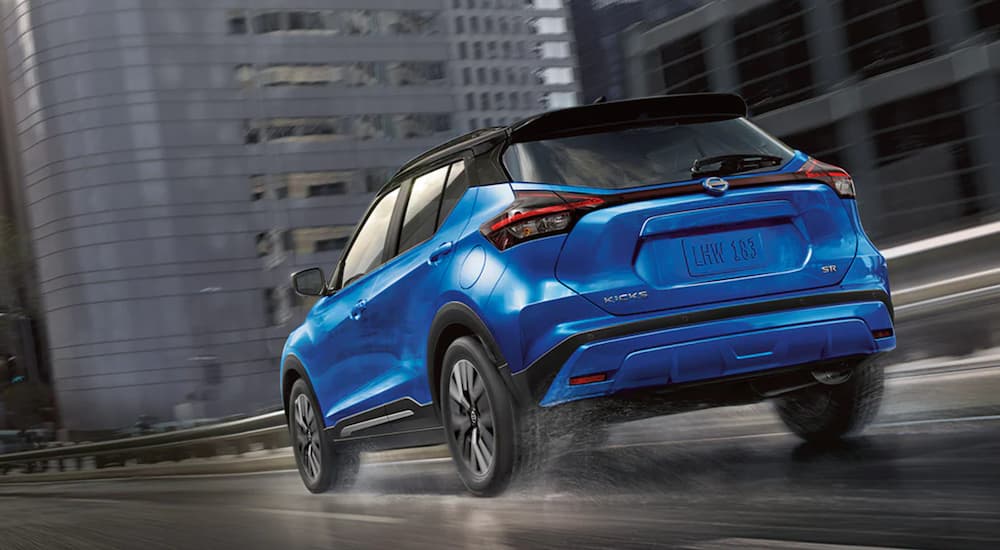Used%20Nissan%20for%20Sale%20-%202021%20Nissan%20Kicks%20-%20Blue.jpg Rear view of a blue 2021 Nissan Kicks driving from a dealer with a used Nissan for sale.