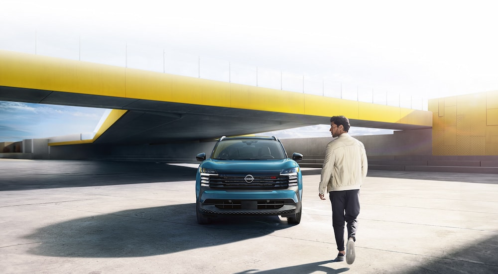 A man walking to a blue 2025 Nissan Kicks SR.