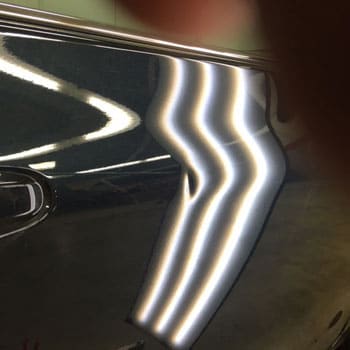 Small dent near door handle before repair at Reliable Collision Center in Springfield Missiouri