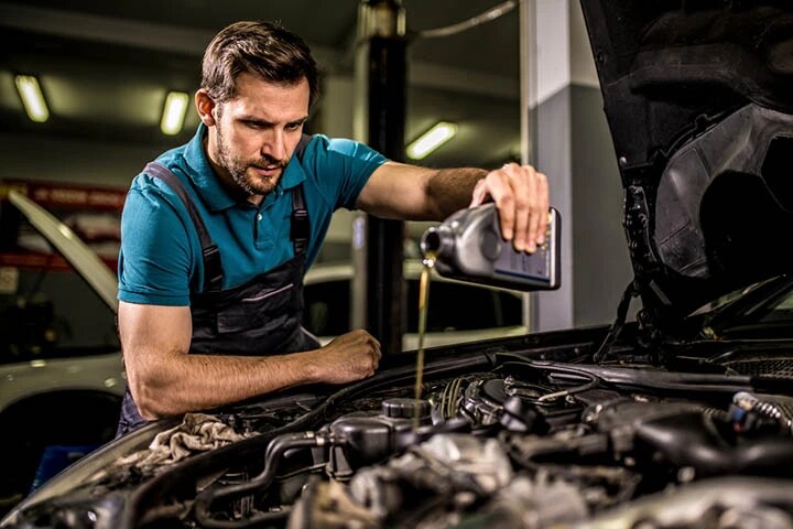 An auto mechanic performs an oil change on the car to improve the vehicle’s fuel efficiency at the car workshop