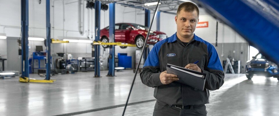 A Ford mechanic holding a clipboard