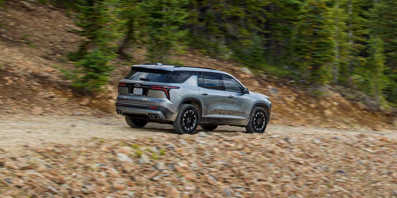 Side Profile View of the 2024 Chevy Traverse Driving on a Gravel Path