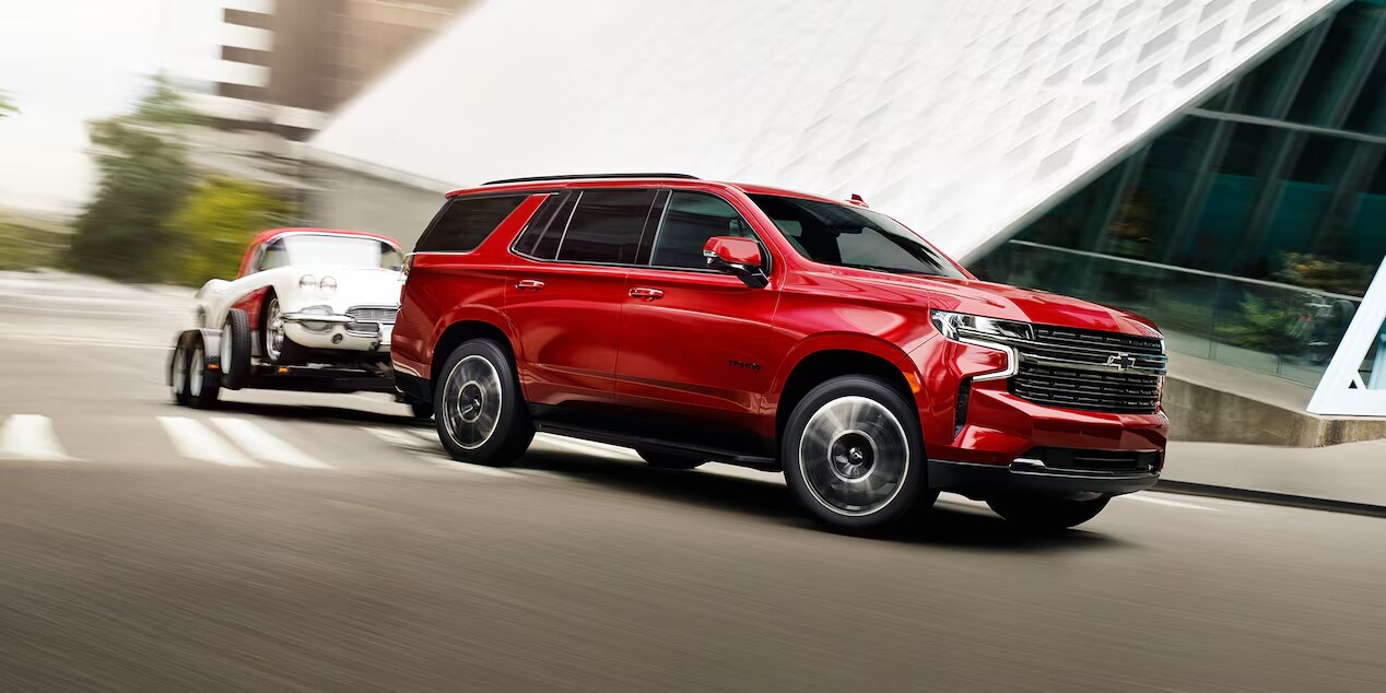 Radiant Red Tintcoat (extra-cost color) Chevrolet Suburban towing a trailer, featuring Radiant Red Tintcoat color and other available features.