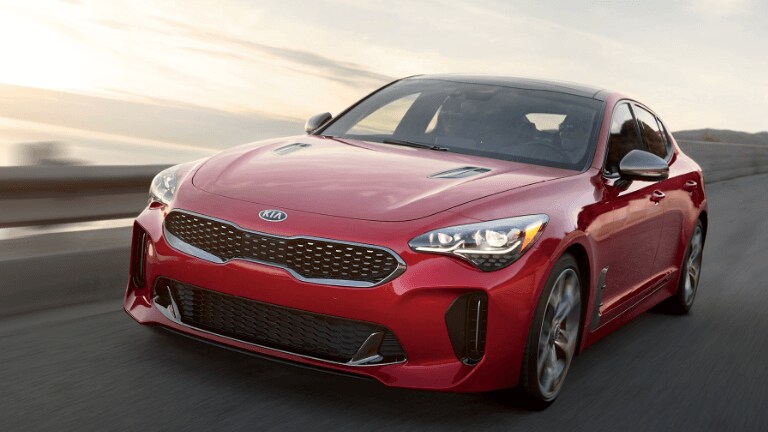 2019 Kia Stinger in red driving on coastal highway