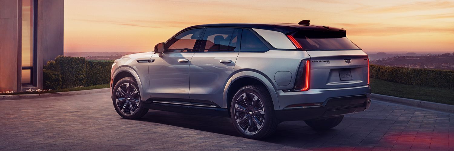 Cadillac Escalade IQ Sport parked in front of building overlooking a sunset New 2025 Escalade