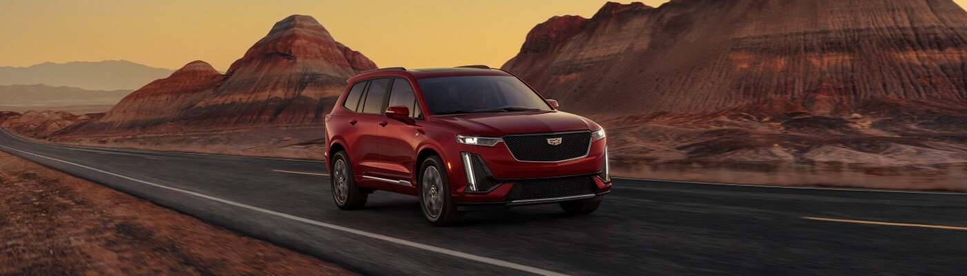 CADILLAC XT6 driving down a two lane road down a desert landscape at sunset new CADILLAC XT6 SUV