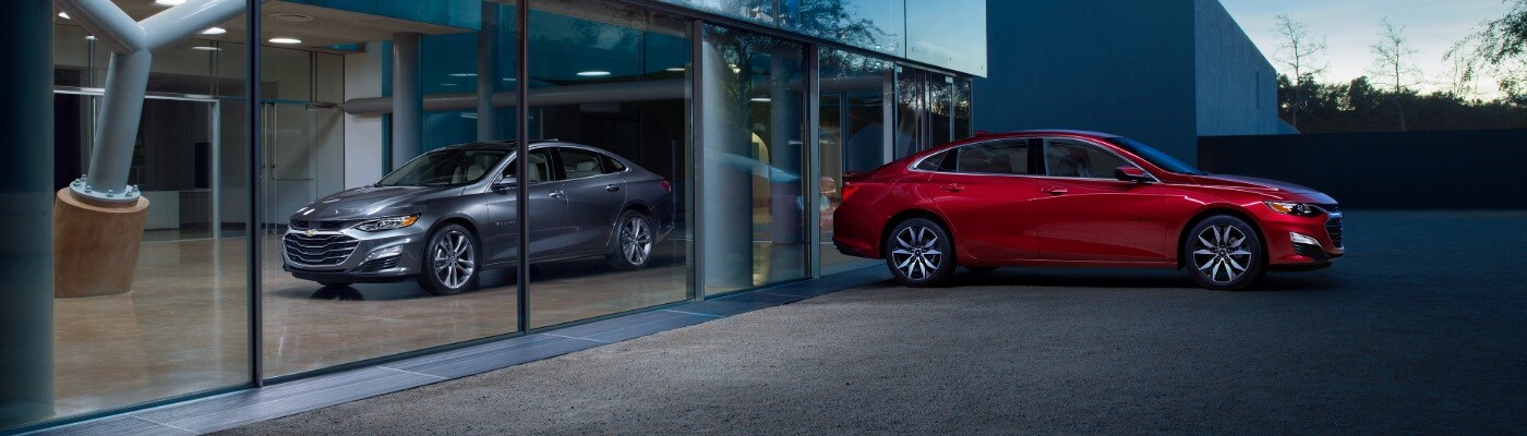 2025 Chevy Malibu Red Chevy Malibu parked by a silver Malibu