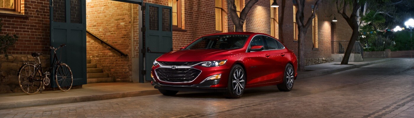 2025 Chevy Malibu 2025 Chevrolet Malibu RS parked on a cobble stone street near a bicycle