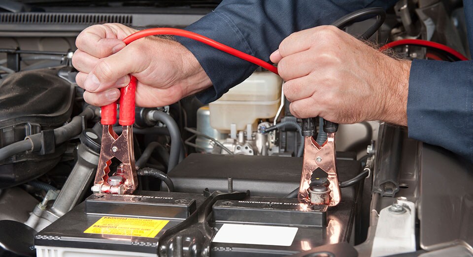 A mechanic charging a car battery
