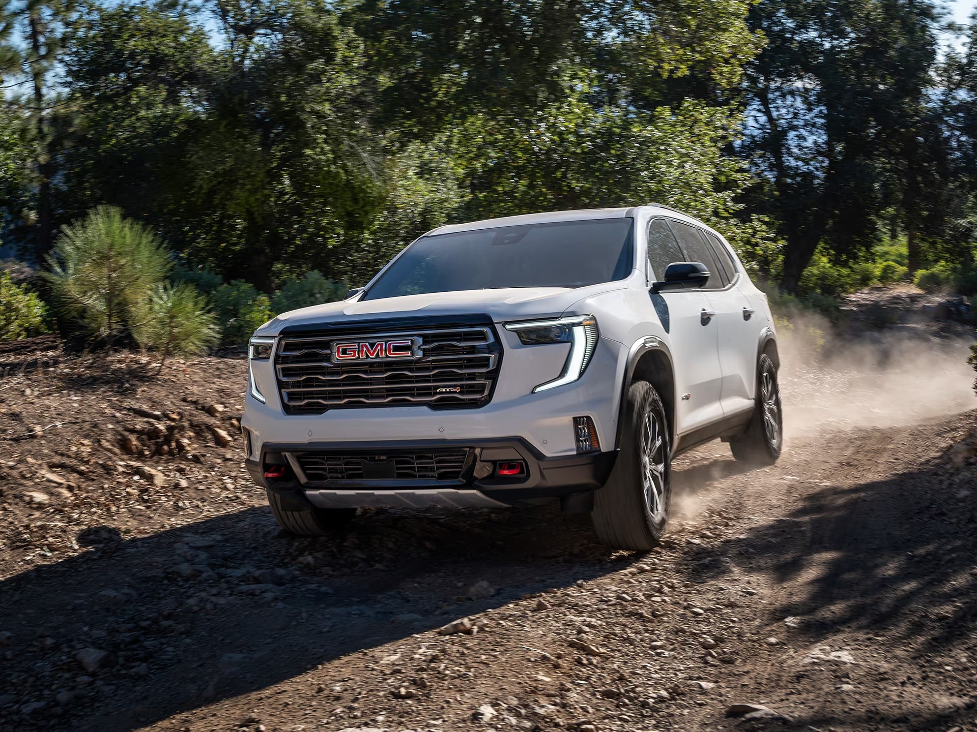 2026 GMC Acadia driving on a winding road, showcasing its performance.