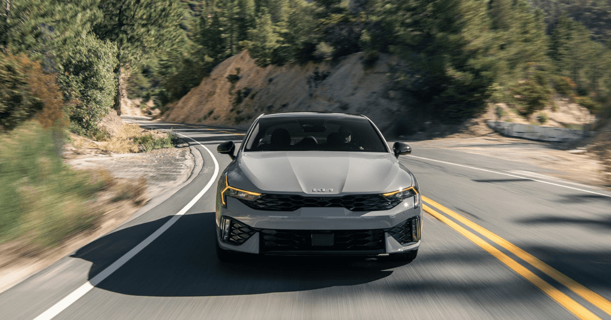 A gray Kia K5 driving down the road