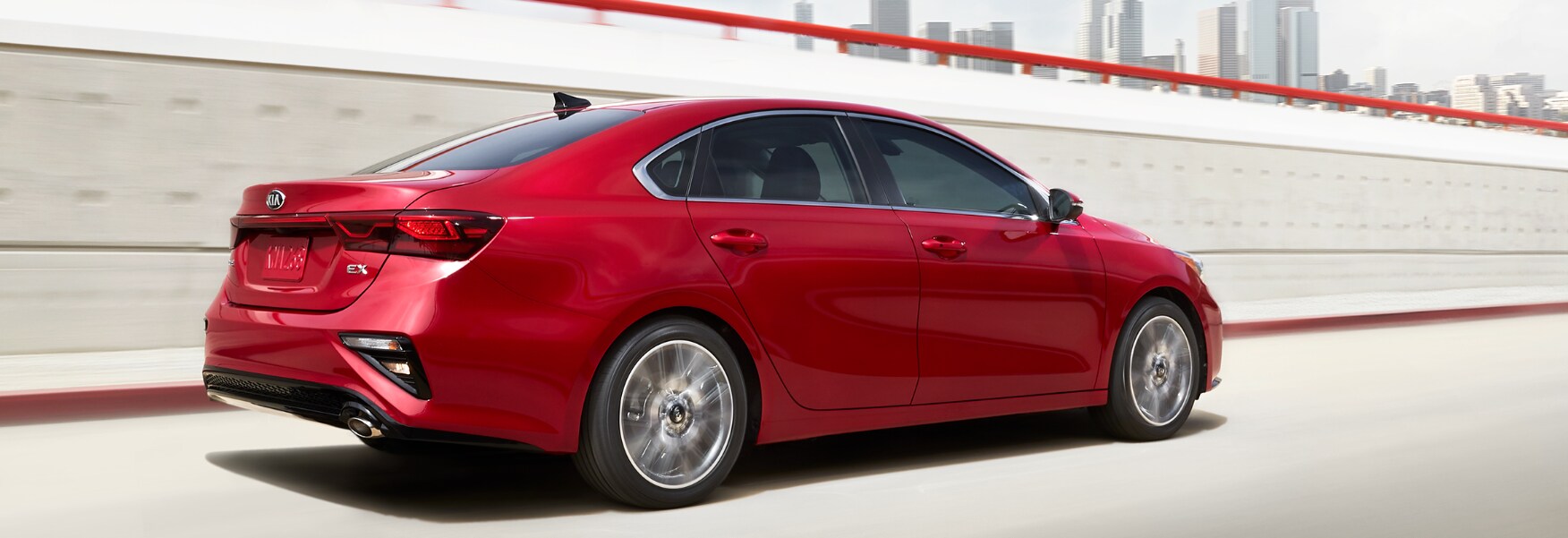 Red 2019 Kia Forte back passenger side view driving past city