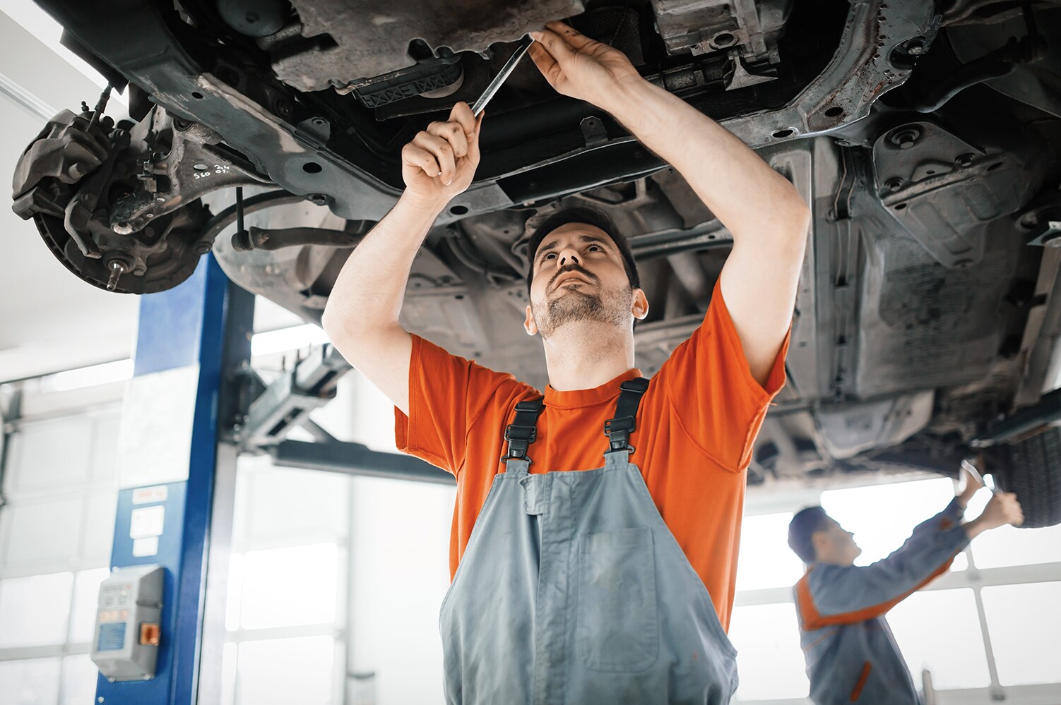 Sale Kia is a Kia Dealership in Kinston near Wilson, NC | Kia mechanic working under vehicle