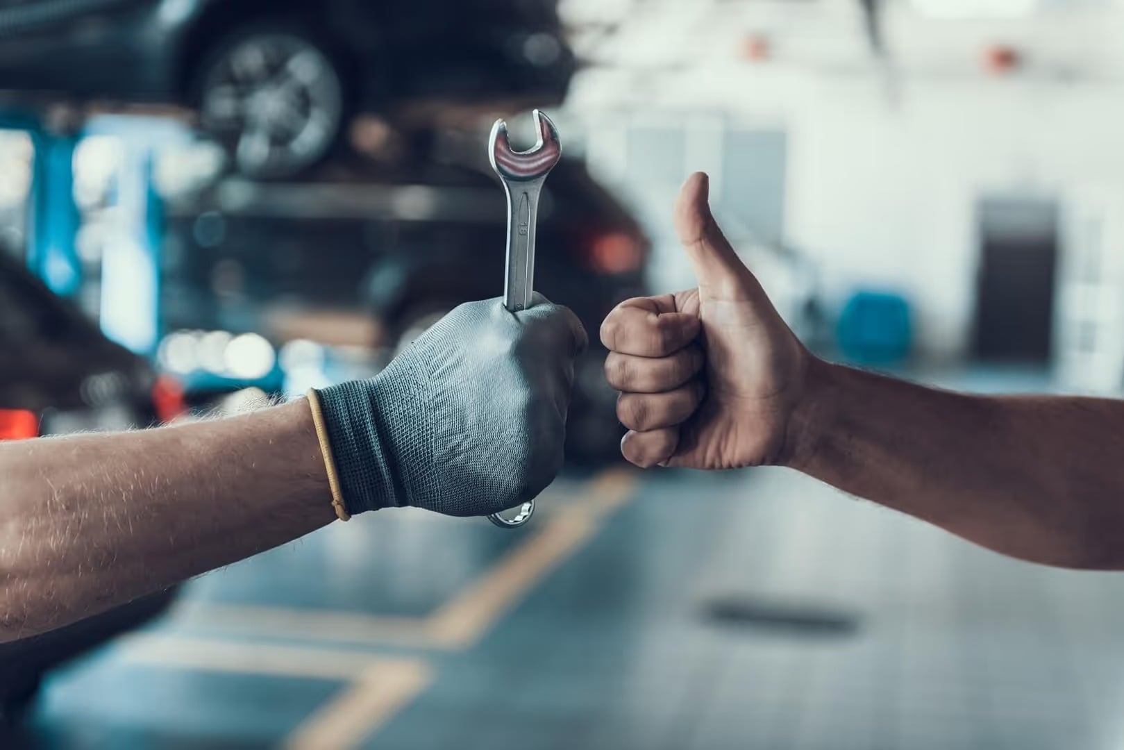 Hyundai technicans' hands - one holding a wrench and the other giving a thumbs up