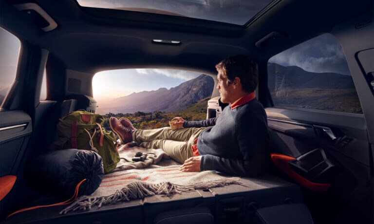 Man laying in the back of a 2020 Audi Q3 watching the sunset