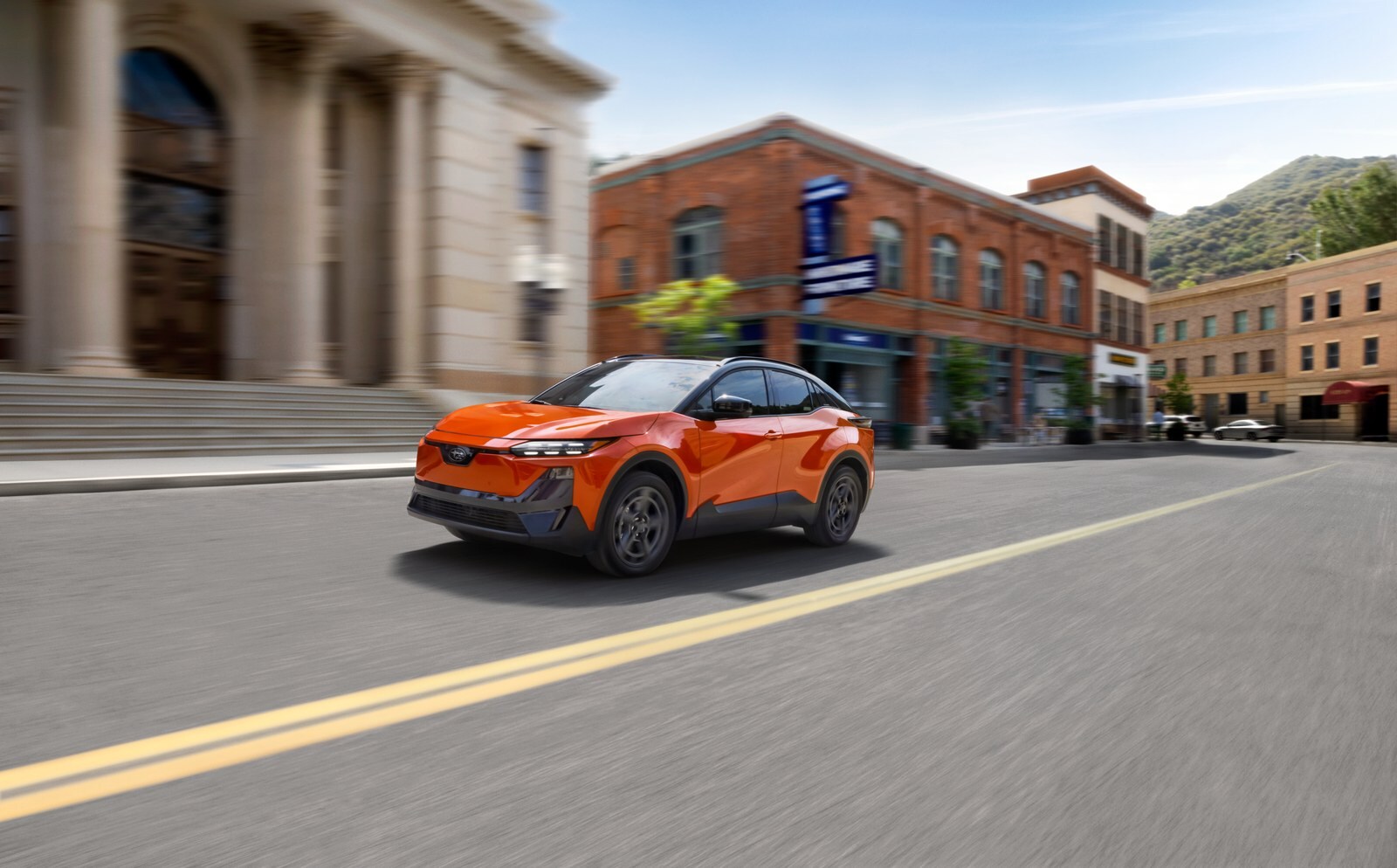 2027 Subaru Uncharted GT in Habanero Orange Metallic Two-Tone driving on a town street