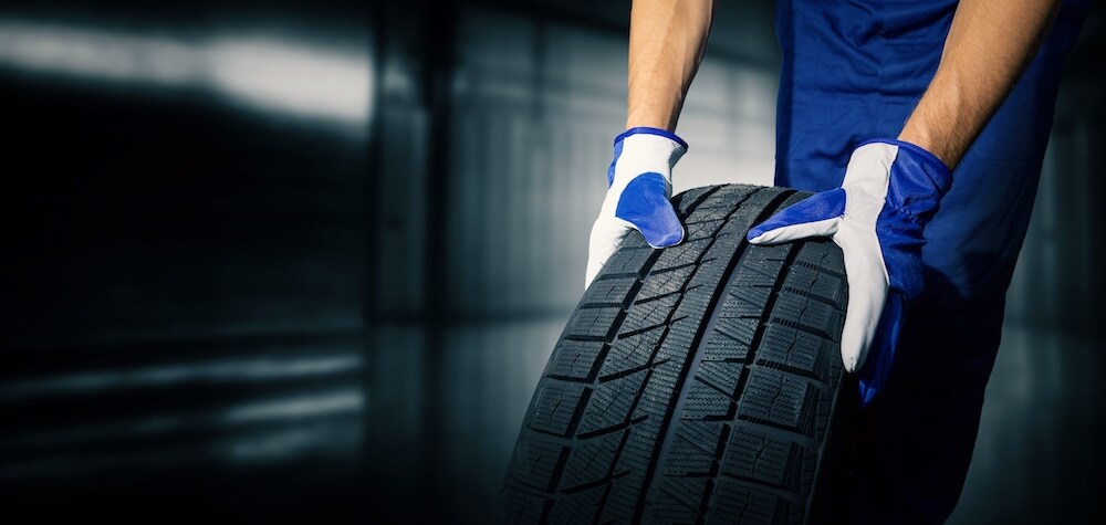 A service technician rolling a new tire A service technician rolling a new tire