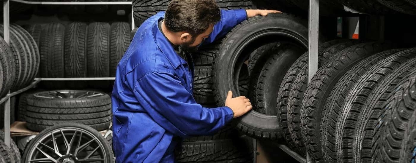 Mechanic pulling a tire from a rack.